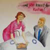 "... und jetzt kommt der Kuchen!" Eine Frau trägt einen Kuchen zu einem Tisch, an dem ein Mann sitzt.