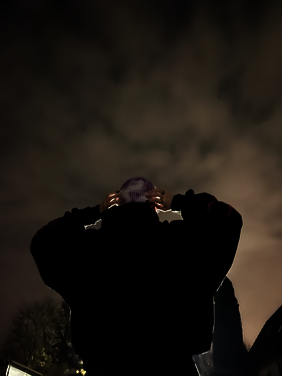 Person von Hinten im dunkel, leuchten von der rechten Ecke. Wolken im Himmel.