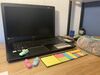 Ein schwarzer Laptop steht aufgeklappt auf einem Schreibtisch