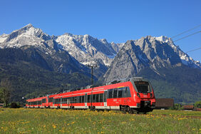 Deutsche Bahn inmitten einer idyllischen Landschaft mit Bergen im Hintergrund und einer Löwenzahnwiese